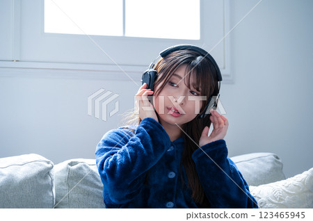 Young woman listening to music with headphones in the living room in winter Young woman listening to music with headphones in the living room in winter 123465945