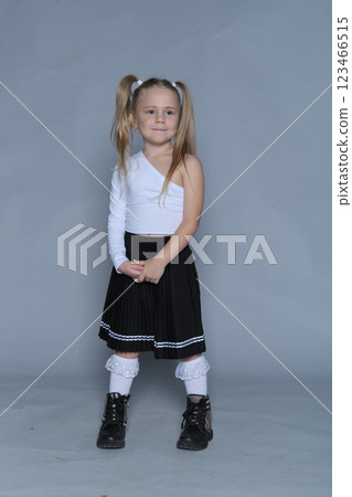 5-year-old girl exudes confidence as she stands tall in a stylish one-shoulder top and pleated skirt. This studio shot emphasizes the empowerment and individuality of children's fashion, highlighting 5-year-old girl exudes confidence as she stands tall in a stylish one-shoulder top and pleated skirt. This studio shot emphasizes the empowerment and individuality of children's fashion, highlighting 123466515