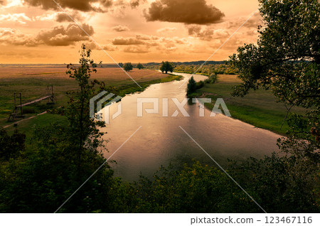 River at sunset. Wonderful view of a calm river illuminated by the warm sunset sun. River at sunset. Wonderful view of a calm river illuminated by the warm sunset sun. 123467116