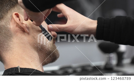 Professional barber carefully shaving client's beard, gripping straight razor with expertise while working in classic barbershop setting 123468789