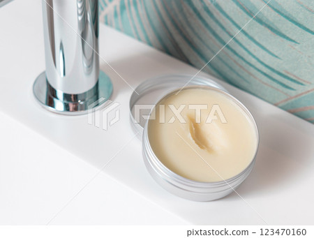 Opened body butter jar on washbasin in green tropical bathroom close up, herbal cosmetic mockup 123470160