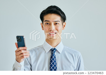 一名身穿襯衫、手持智慧型手機的年輕人 123470463