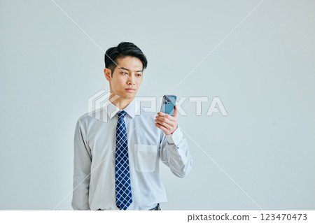 一名身穿襯衫、手持智慧型手機的年輕人 123470473