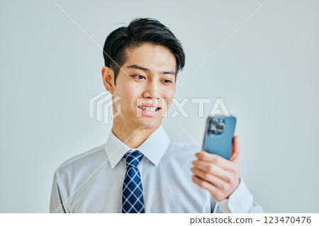 A young man in a shirt holding a smartphone 123470476