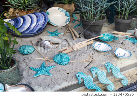 Shop window with ceramics on the sand. Ceramics on a marine theme, plates, shells and sea turtles. Shop window with ceramics on the sand. Ceramics on a marine theme, plates, shells and sea turtles. 123470550