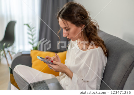 Woman Home Smartphone: Using mobile phone indoors, relaxing on sofa, modern lifestyle. Woman Home Smartphone: Using mobile phone indoors, relaxing on sofa, modern lifestyle. 123471286