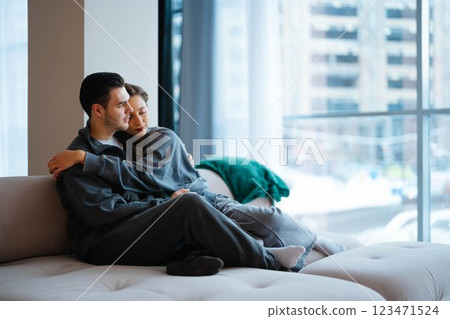 Cozy couple embraces in modern apartment with city view during daytime Cozy couple embraces in modern apartment with city view during daytime 123471524