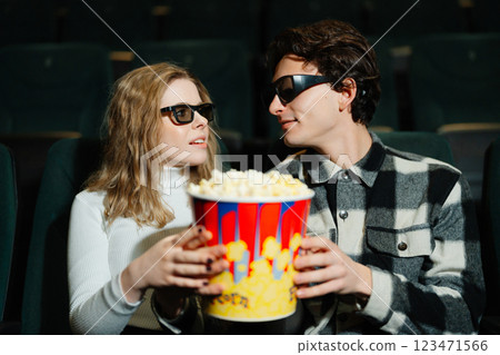 Couple enjoying popcorn and a movie in a theater with 3D glasses 123471566