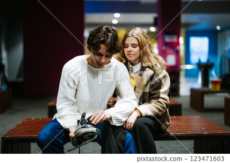 Young couple enjoys ice skating together while getting ready at rink 123471603