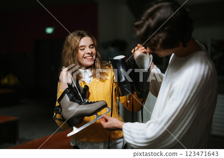 Young adults prepare for ice skating session at a rink during winter evening 123471643