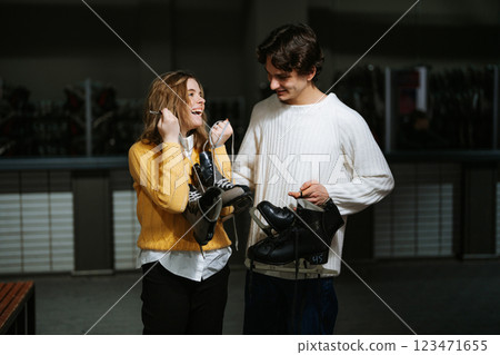Young couple enjoying time together while holding skates indoors Young couple enjoying time together while holding skates indoors 123471655