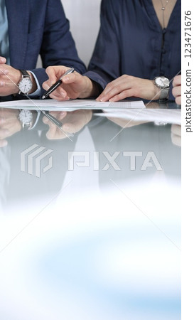 Unrecognizable business people are discussing a contract during meeting while sitting at the glass table in office, vertical close up view. Copy space area 123471676