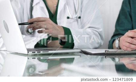 Female doctor showing medical exam results on a laptop to a patient during a visit at the clinic, healthcare and medical consultation concept 123471809