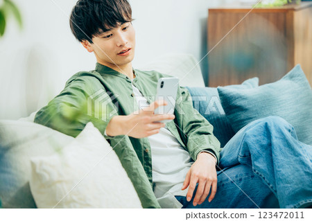 A young man looking at his smartphone in the living room A young man looking at his smartphone in the living room 123472011