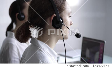 Young female call center operator in white blouse is assisting clients online, providing customer support and answering inquiries. Business call center Young female call center operator in white blouse is assisting clients online, providing customer support and answering inquiries. Business call center 123472134