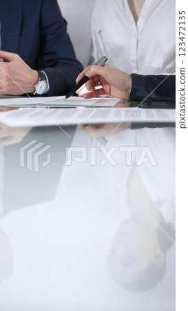 Unrecognizable business people are reviewing contract terms during a meeting while sitting at the glass table in office, vertical close up view. Copy space area Unrecognizable business people are reviewing contract terms during a meeting while sitting at the glass table in office, vertical close up view. Copy space area 123472135