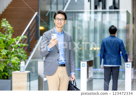 Businessman holding a smartphone in front of the ticket gate Businessman holding a smartphone in front of the ticket gate 123472334
