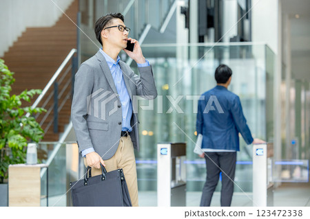 Businessman holding a smartphone in front of the ticket gate 123472338