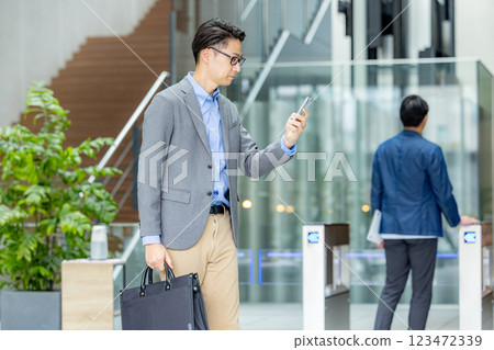 Businessman holding a smartphone in front of the ticket gate 123472339