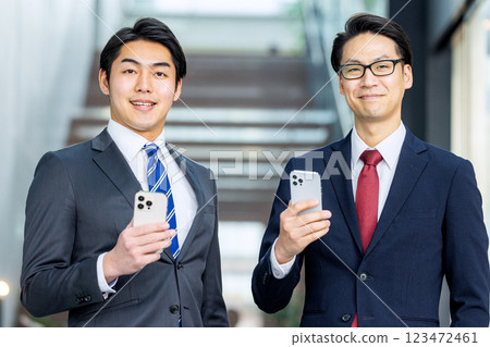 一個穿著西裝的男人拿著智能手機 123472461