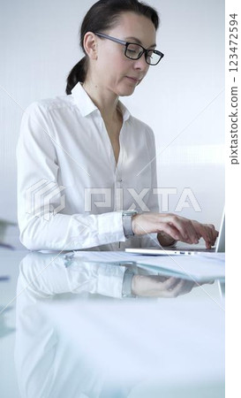 Classical dressed businesswoman is using a laptop in a contemporary office, with a clean, bright environment. Business people concept 123472594