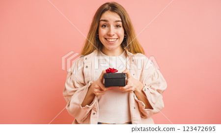 Happy woman holding a gift box on pink background 123472695