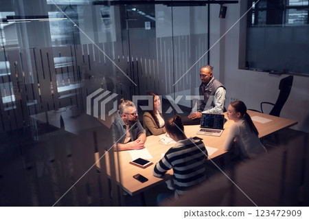 A diverse team of young professionals collaborates in a modern office conference room. Businesspeople discuss strategy, technology, and planning, using laptops to develop an innovative e-commerce 123472909