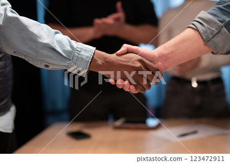 Business professionals shake hands in an office, sealing a successful agreement. A corporate meeting highlights teamwork, trust, and collaboration, welcoming a new employee and strengthening 123472911