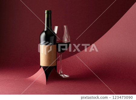 Bottle and glass of red wine on a red background. 123473090