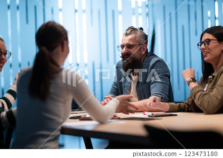 A diverse team of young professionals collaborates in a modern office conference room. Businesspeople discuss strategy, technology, and planning, using laptops to develop an innovative e-commerce 123473180