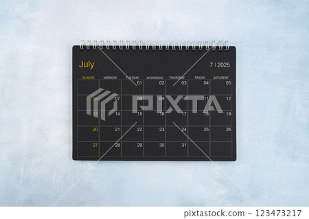 Blank calendar for July 2025, Black spiral desktop calendar on wooden background. 123473217
