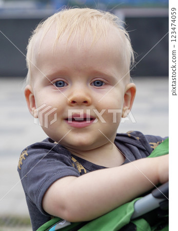 Bright-eyed toddler enjoying a sunny day outdoors while being held in a stroller 123474059