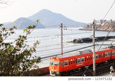 A train on the Iyotetsu Takahama Line runs with Mount Iyo-Kofuji on Gogoshima Island in the background. A train on the Iyotetsu Takahama Line runs with Mount Iyo-Kofuji on Gogoshima Island in the background. 123475282