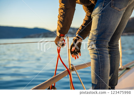 Young man captain operates and controls a sailboat during a journey by sea in winter time in Montenegro 123475998