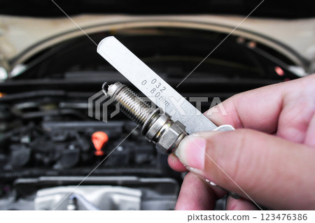 Close up of spark plug and feeler gauge or thickness gauge in hand to adjust the gap of spark plug Close up of spark plug and feeler gauge or thickness gauge in hand to adjust the gap of spark plug 123476386