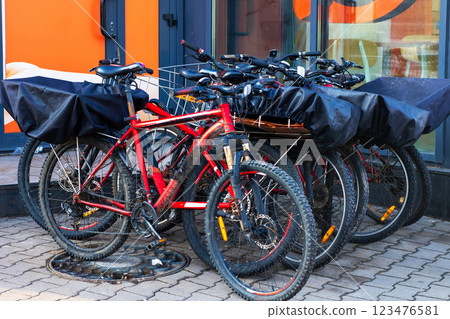 A neat row of bicycles is parked in front of a specific building 123476581