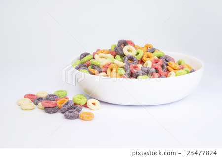 Delicious and nutritious fruit cereal loops multicolored flavorful on white background, healthy and funny addition to kids breakfast Delicious and nutritious fruit cereal loops multicolored flavorful on white background, healthy and funny addition to kids breakfast 123477824