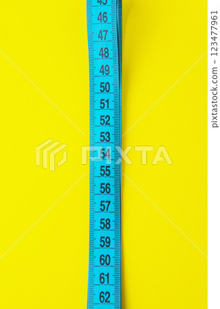 Blue tape measure diet concept on yellow background with copyspace Blue tape measure diet concept on yellow background with copyspace 123477961