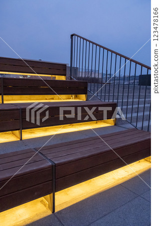 Wooden step and seating with lighting underneath, with metal handrail on the side 123478166