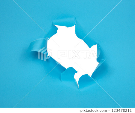 Hole in paper blue background torn damaged for design 123478211