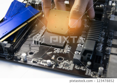 The technician is installing the CPU onto the motherboard. 123478852