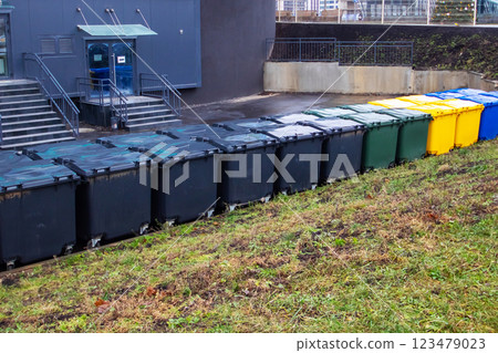 A row of trash cans is neatly lined up in front of an old building 123479023