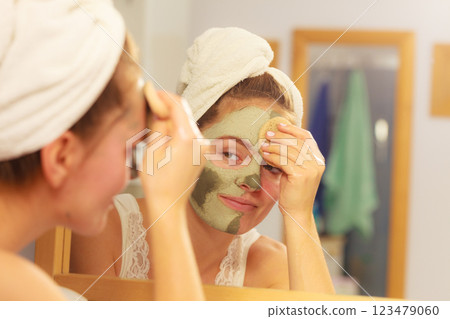 Woman removing facial clay mud mask in bathroom Woman removing facial clay mud mask in bathroom 123479060