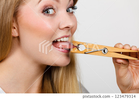Blonde woman having tongue in clothespin Blonde woman having tongue in clothespin 123479314