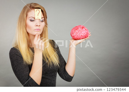 Woman thinking and holding fake brain Woman thinking and holding fake brain 123479344