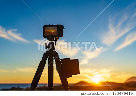 Camera on tripod taking picture of sunset over coast 123479419