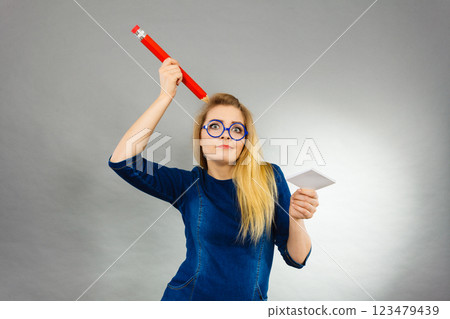 Confused woman holds big pencil note paper in hand Confused woman holds big pencil note paper in hand 123479439
