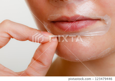 Woman removing facial peel off mask closeup Woman removing facial peel off mask closeup 123479446