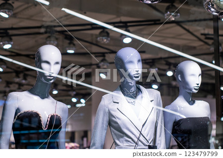 In a store window, there are three mannequins being displayed artistically 123479799