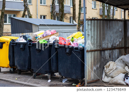 A series of garbage cans are neatly lined up along the side of the road 123479849